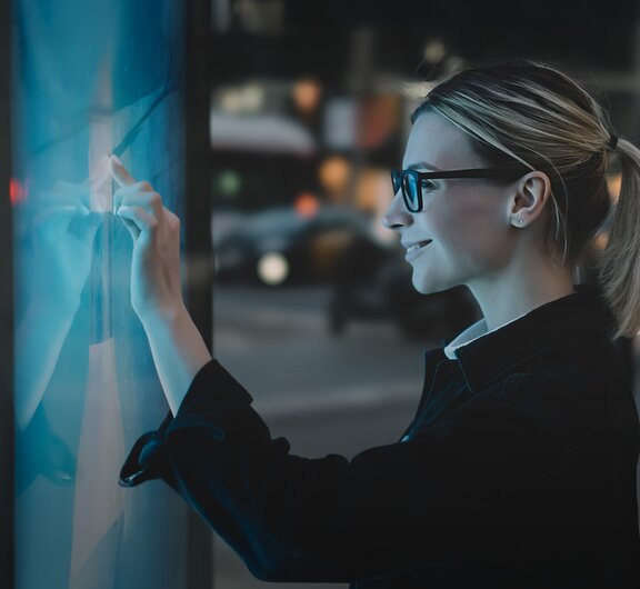 A woman smiles as she works on a large touchscreen.