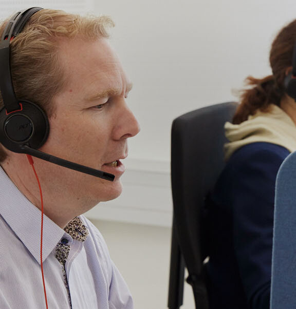 Zwei Mitarbeitende des Serviceteams telefonieren über Headset.
