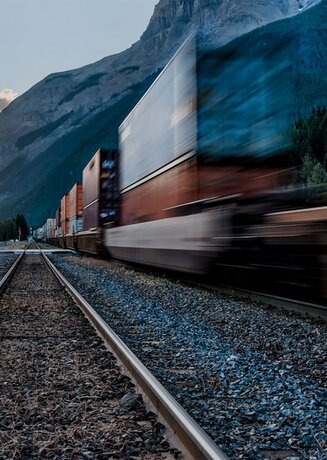 Ein Güterzug, der auf den Gleisen inmitten majestätischer Berge gleitet.